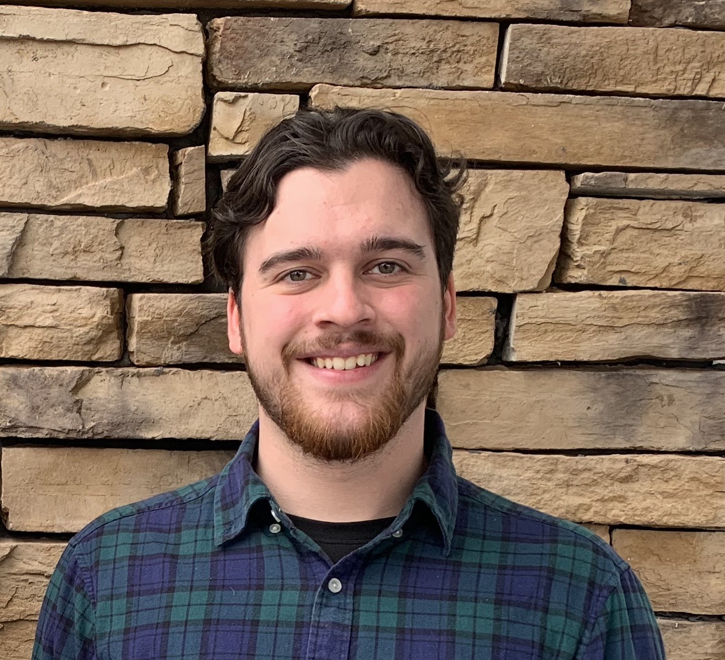 Matt Swartout, Regional Planner at the Commonwealth Regional Council, smiling in front of a stacked stone wall.